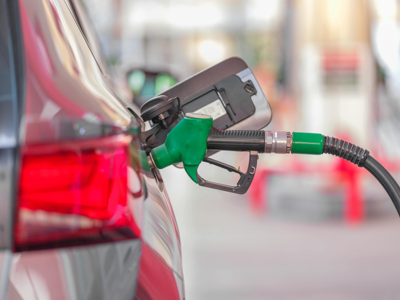 A close-up view of a fuel pump nozzle inserted into a car's tank at a gas station.