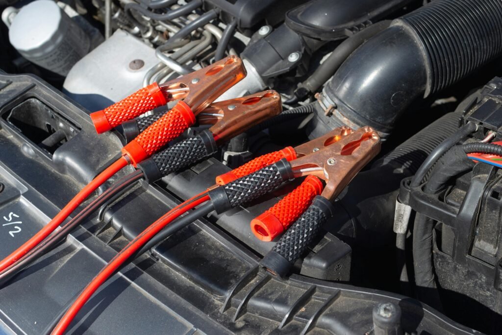 Close-up of car engine with attached jump starter cables, showing detailed mechanics.